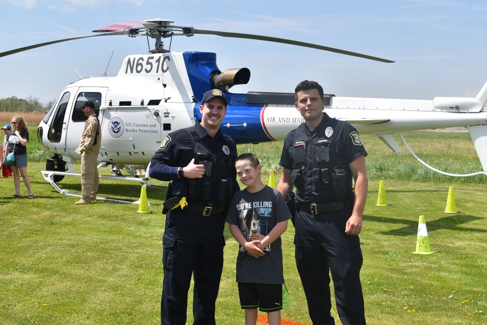 Officers with a young visitor beside a helicopter at the police open house