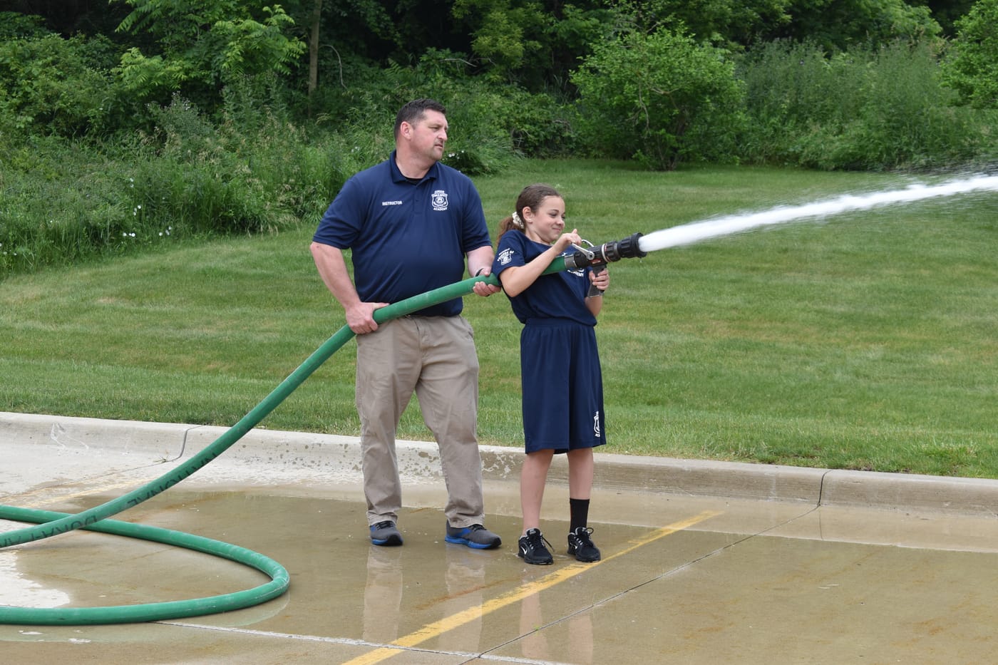 Academy student handling a fire hose with a firefighter