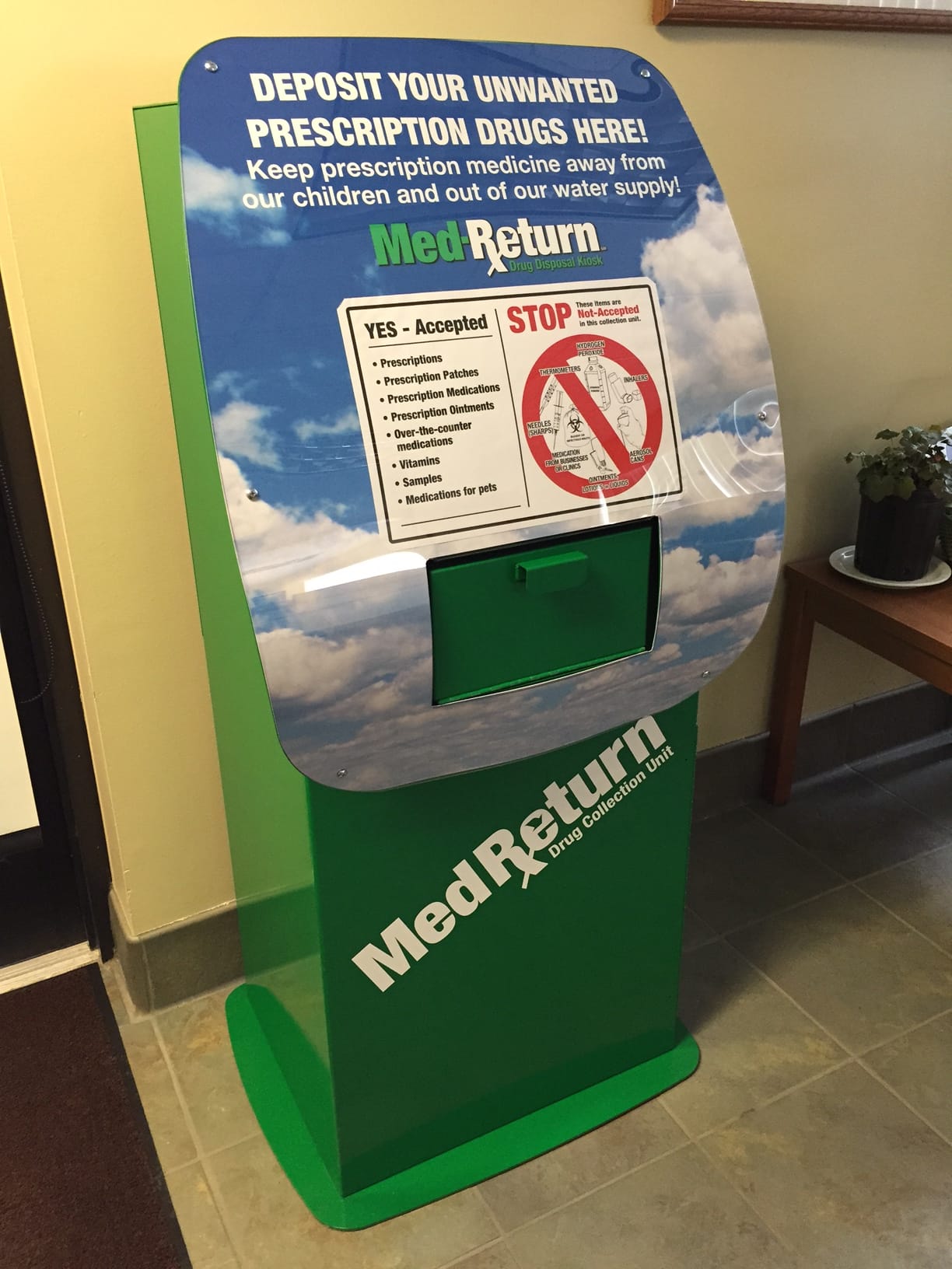 The green Med Return drop-off bin in the police station lobby